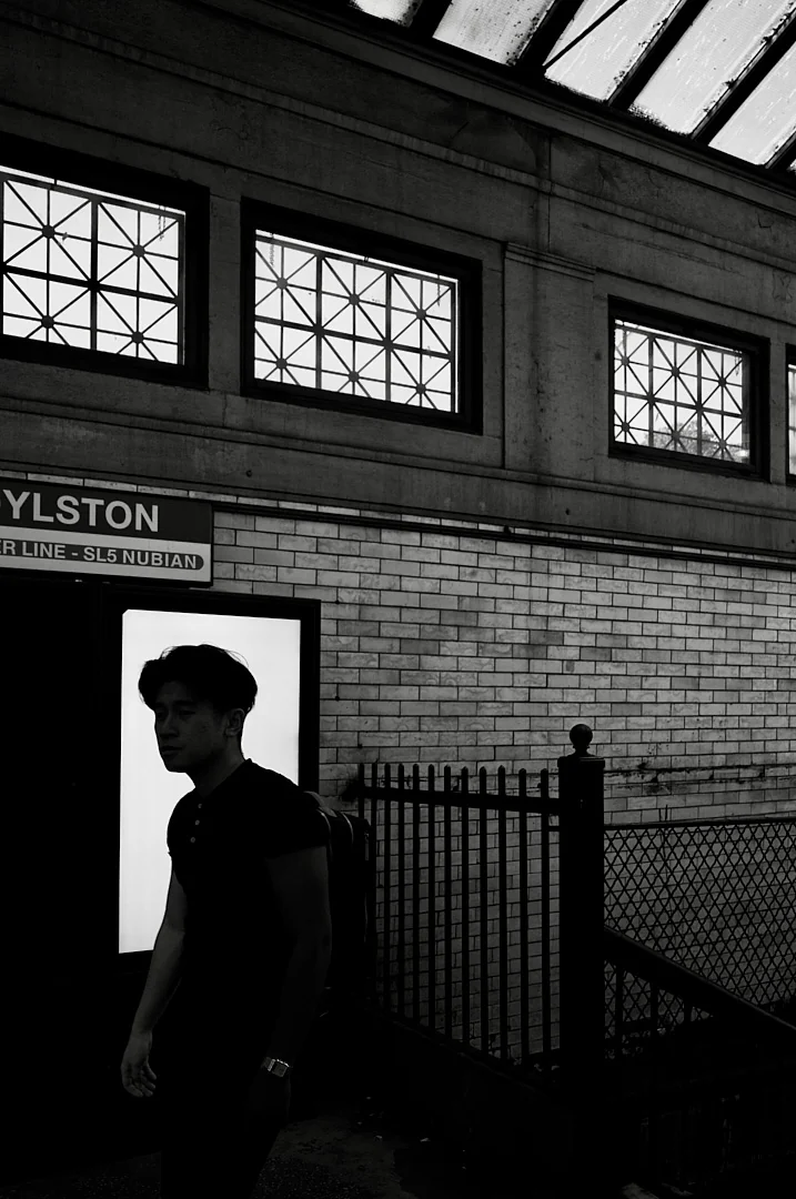 Young man walking past a lit doorway at the Boylston subway entrance
